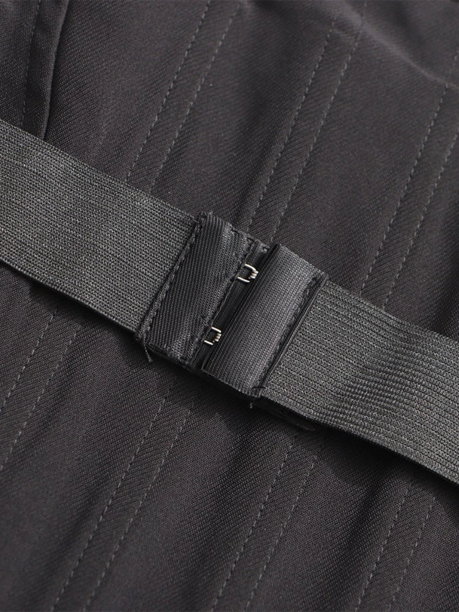 Close-up of a black belt with stitching detail on a textured fabric background